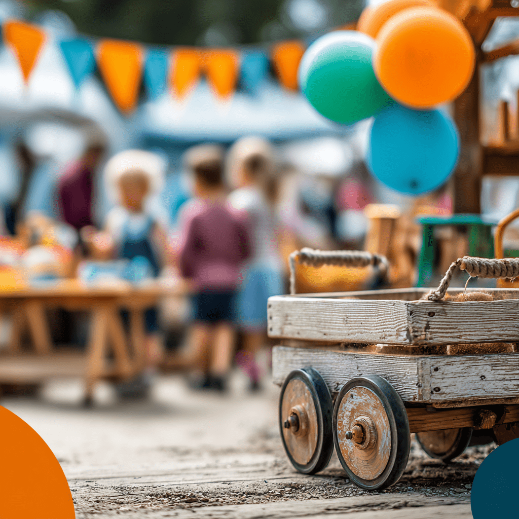 Auf einem Fest für Kinder in der Kita Landwehr sind bunte Luftballons und eine Holzkarre zu sehen. Im Hintergrund sind spielende Kinder und festlich dekorierte Tische.